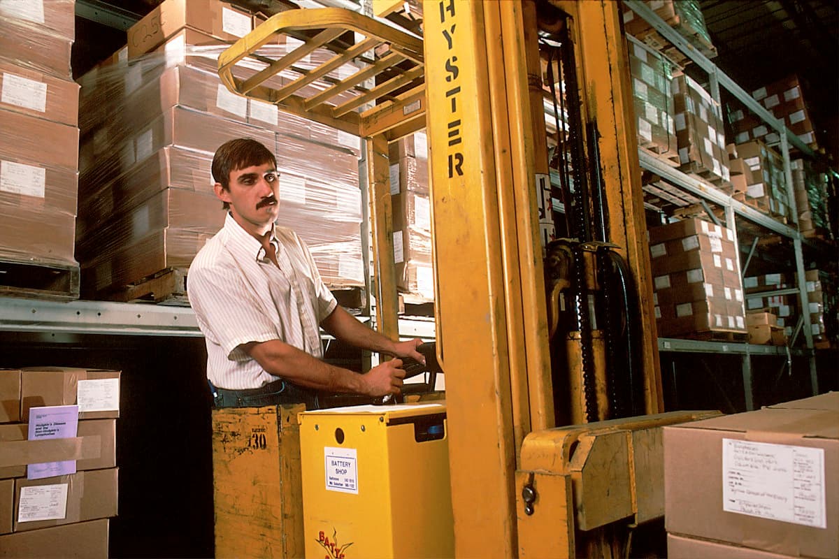 A forklift operator moving pallets inside a warehouse